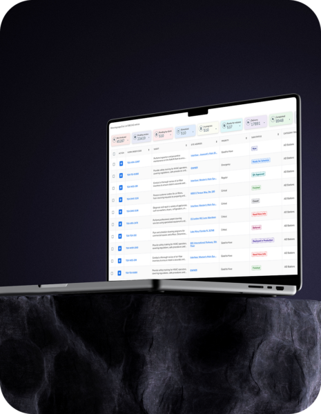 A silver laptop displaying a list-based user interface on a dark background with a textured stone-like surface.