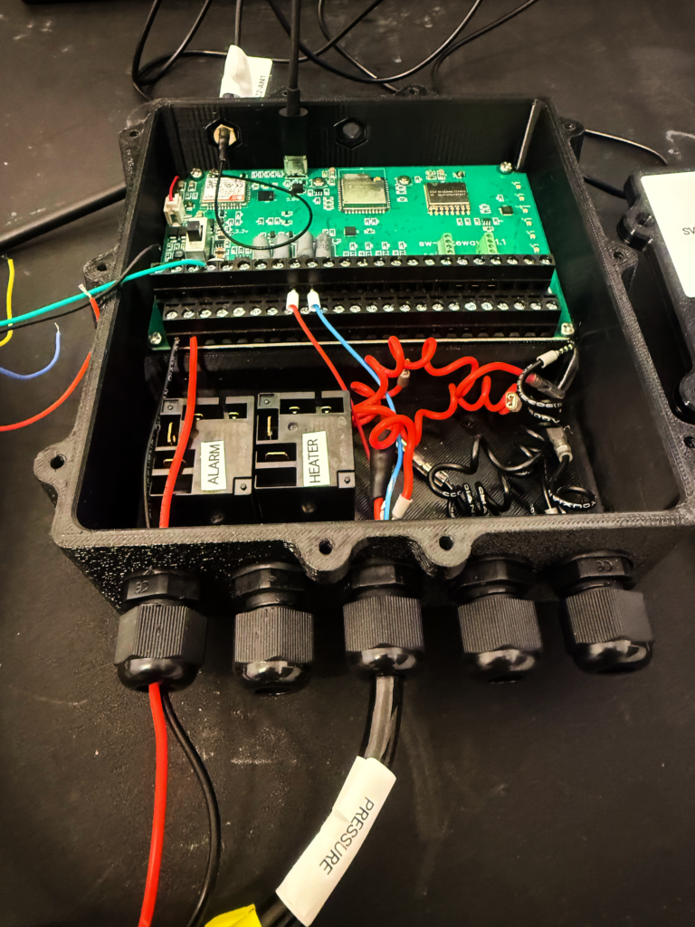 Open electronic box with circuit board, wiring, and labeled components.
